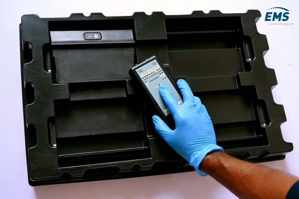 Technician in ESD gloves placing a component into a conductive tray, EMS Technologies
