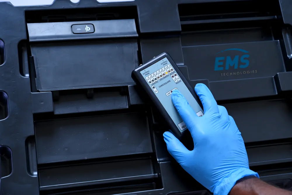 Technician in ESD gloves placing a component into a conductive tray, EMS Technologies